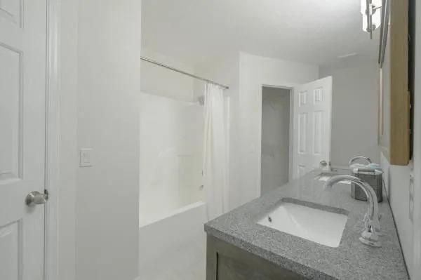 A bathroom with a sink , mirror and bathtub.
