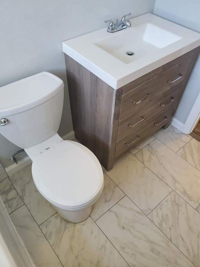 A bathroom with a toilet , sink and dresser.