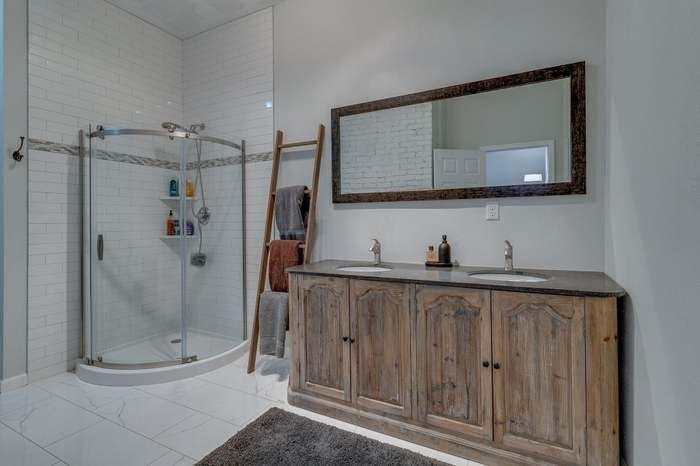 A bathroom with two sinks , a shower and a large mirror.