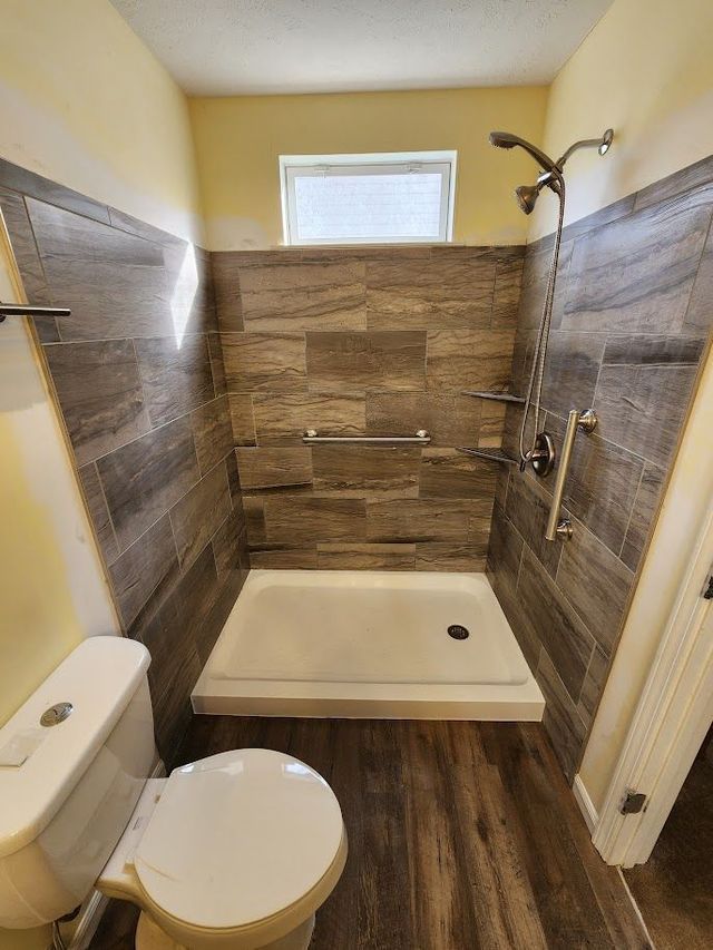 A bathroom with a toilet , shower , and window.
