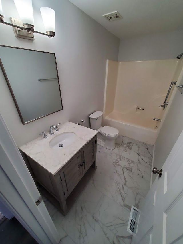 A bathroom with a sink , toilet , bathtub and mirror.