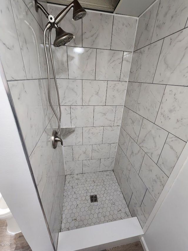A shower with white tiles and a shower head.