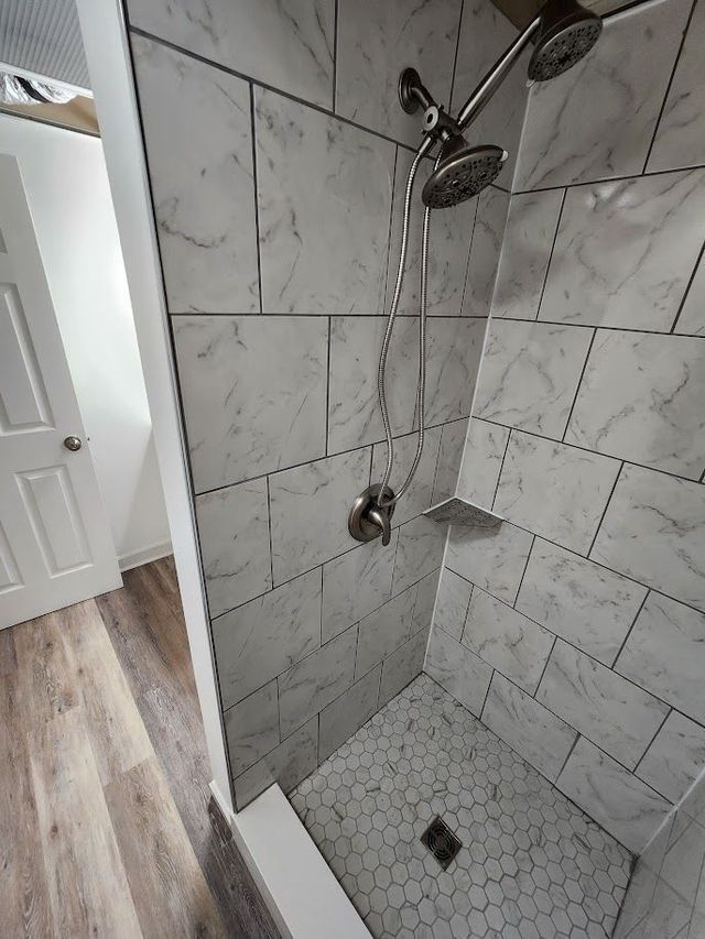 A shower with marble tiles and a shower head in a bathroom.