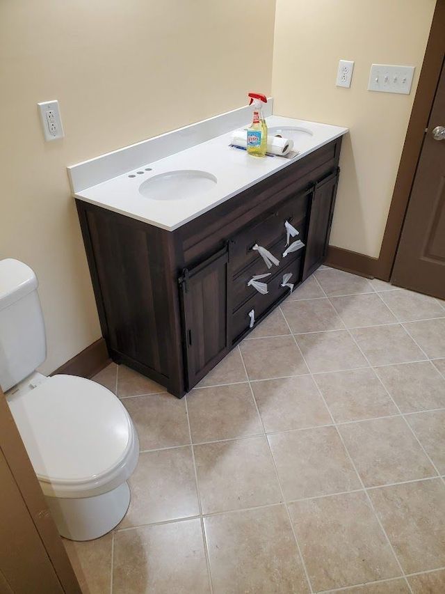 A bathroom with a toilet , sink and vanity.