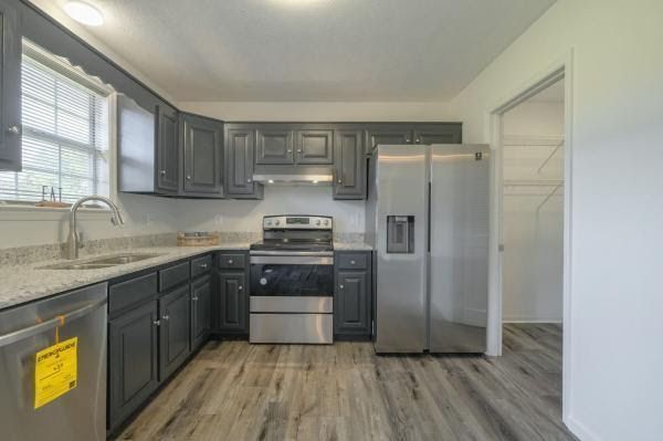 A kitchen with stainless steel appliances and gray cabinets.