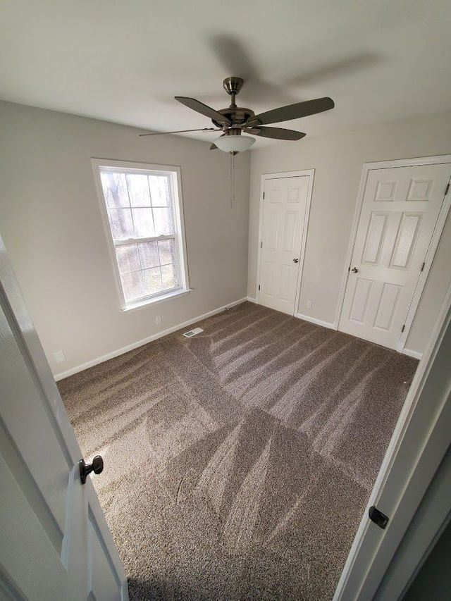 A bedroom with a ceiling fan and a window.