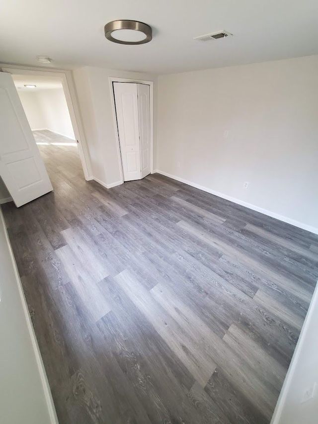 An empty room with hardwood floors and white walls.