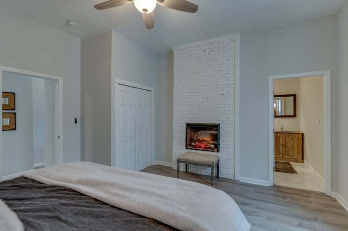 A bedroom with a fireplace and a ceiling fan.
