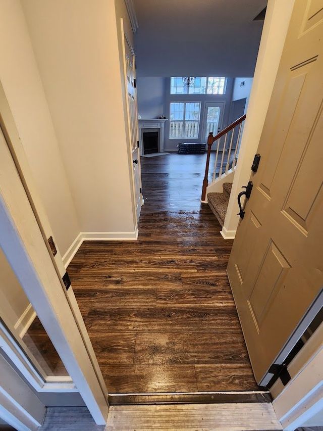 A hallway with hardwood floors and stairs leading to a living room.