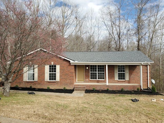 A brick house with a gray roof and white shutters