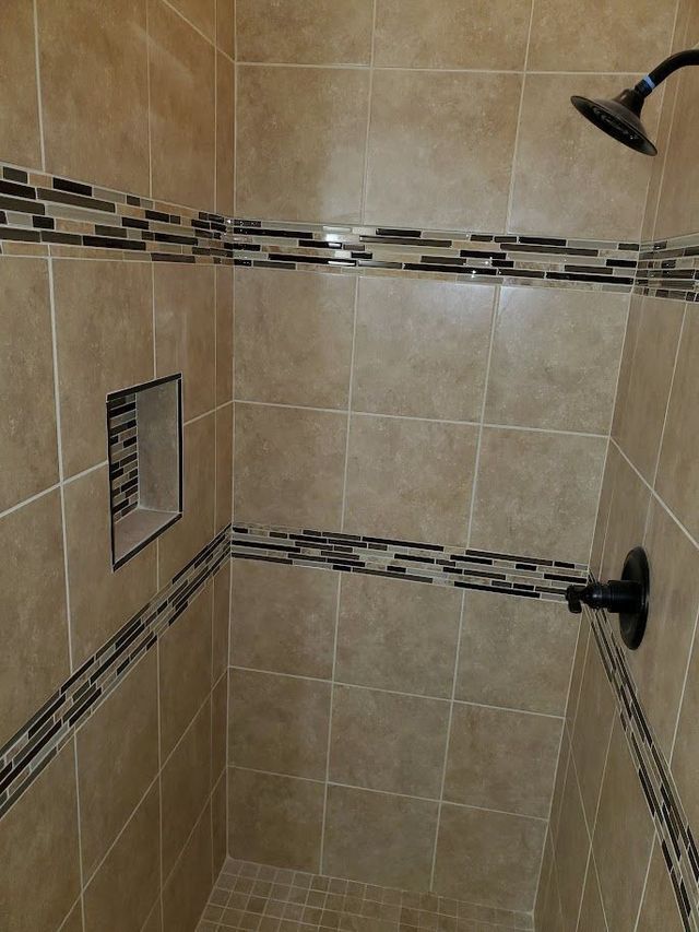 A shower with a shower head and a mirror on the wall.