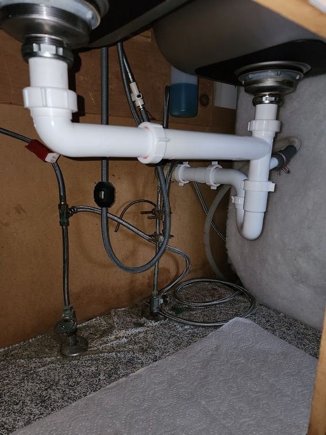 A sink with a lot of pipes underneath it.