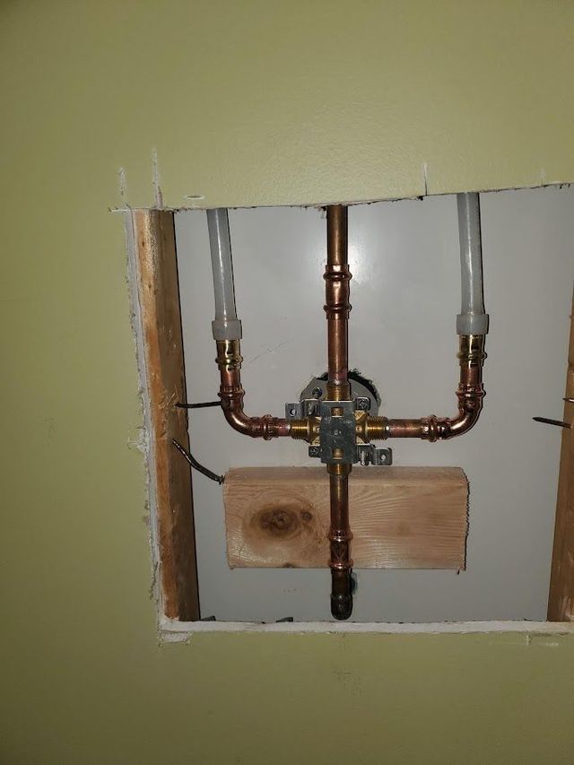 A hole in a wall with copper pipes coming out of it