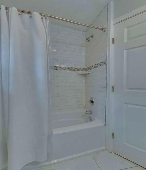 A bathroom with a bathtub and a shower curtain.
