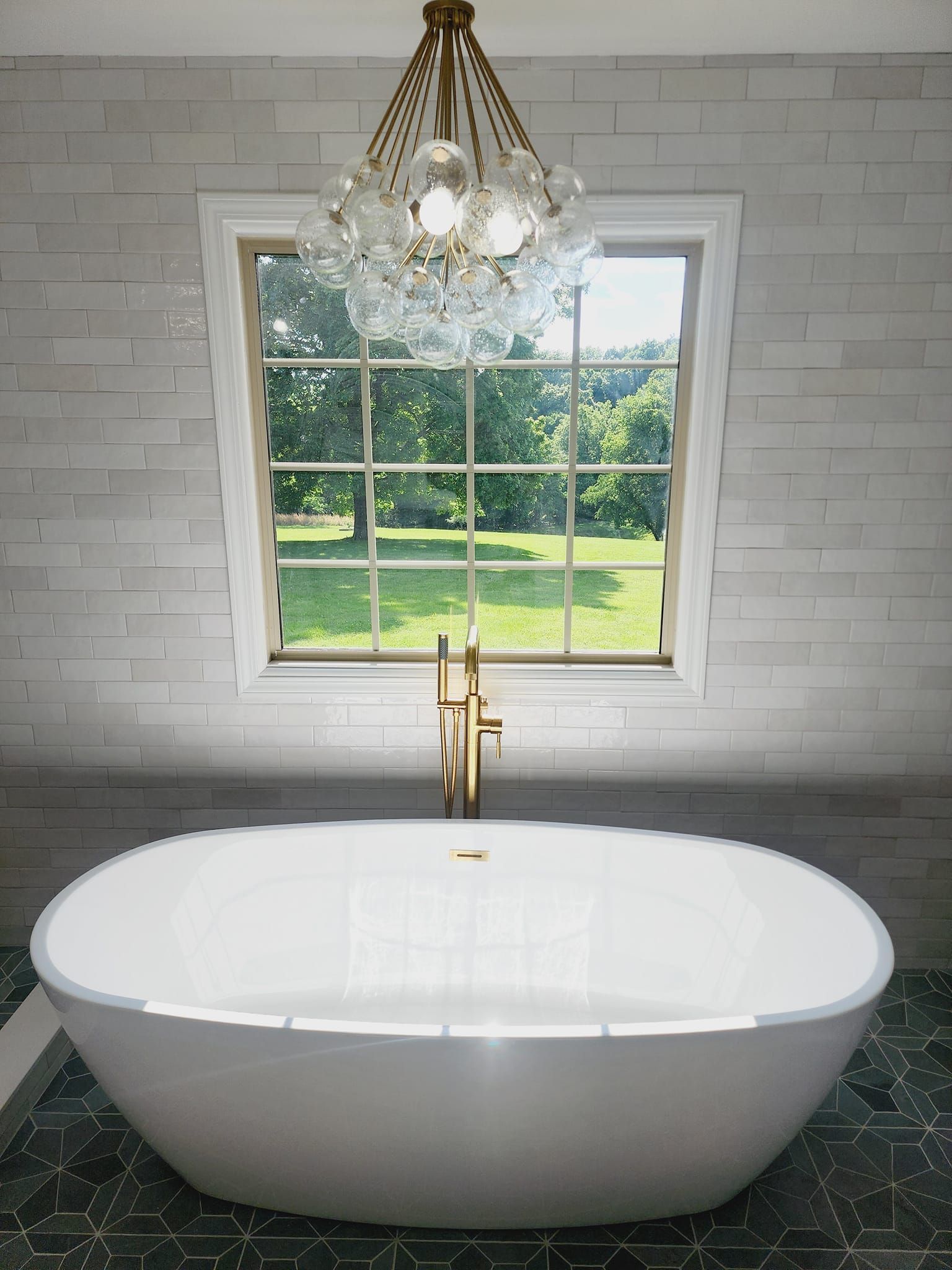 A bathtub in a bathroom with a window and a chandelier