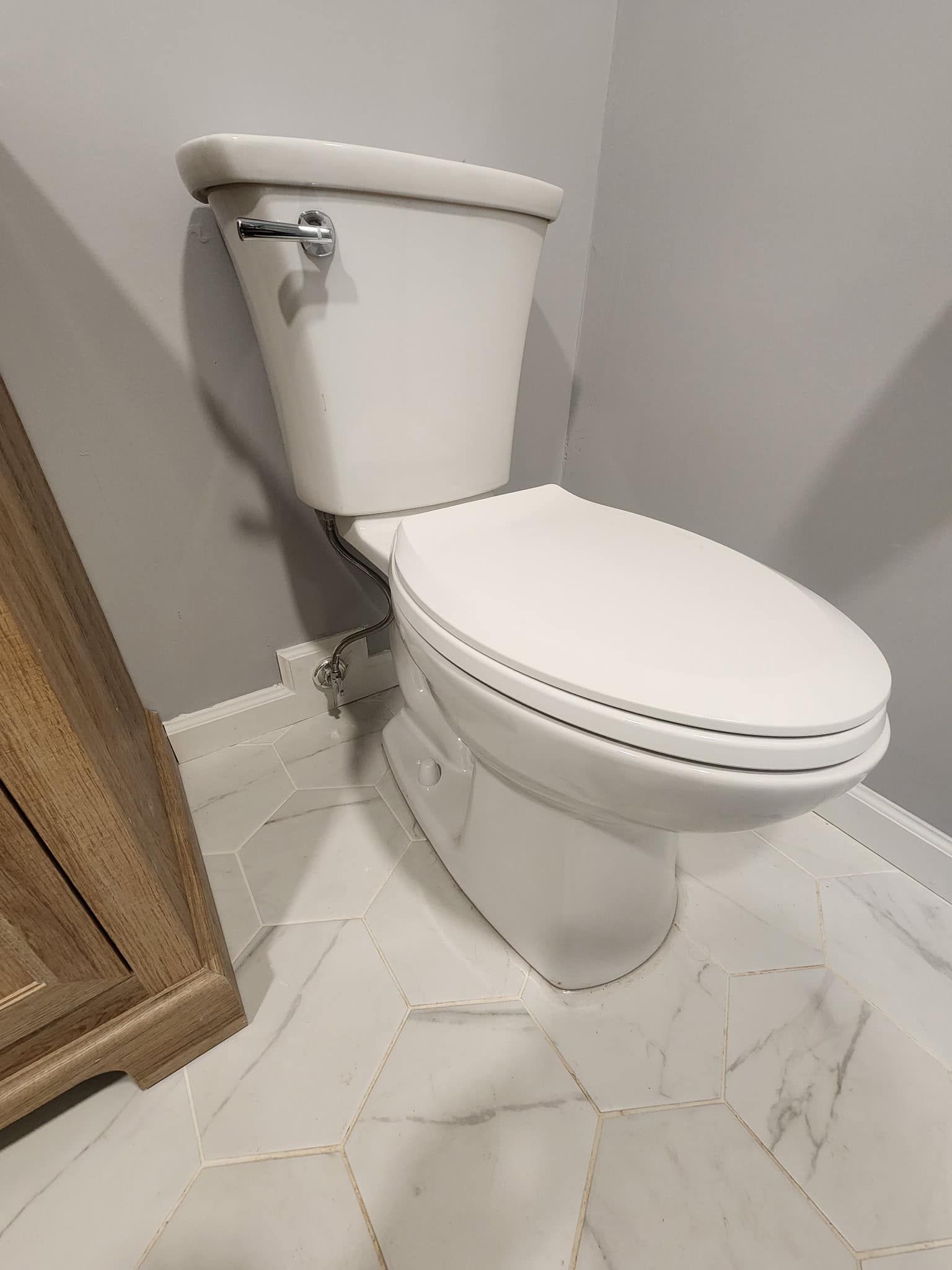 A white toilet is sitting on a tiled floor in a bathroom