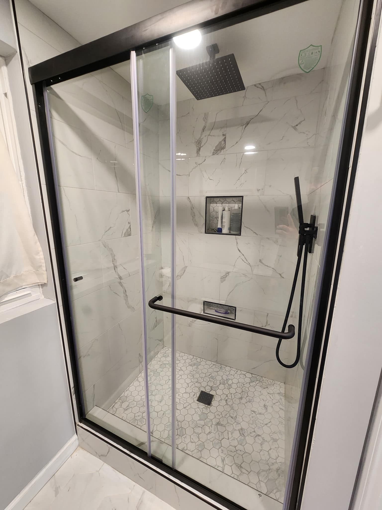 A bathroom with a sliding glass shower door and a black shower head