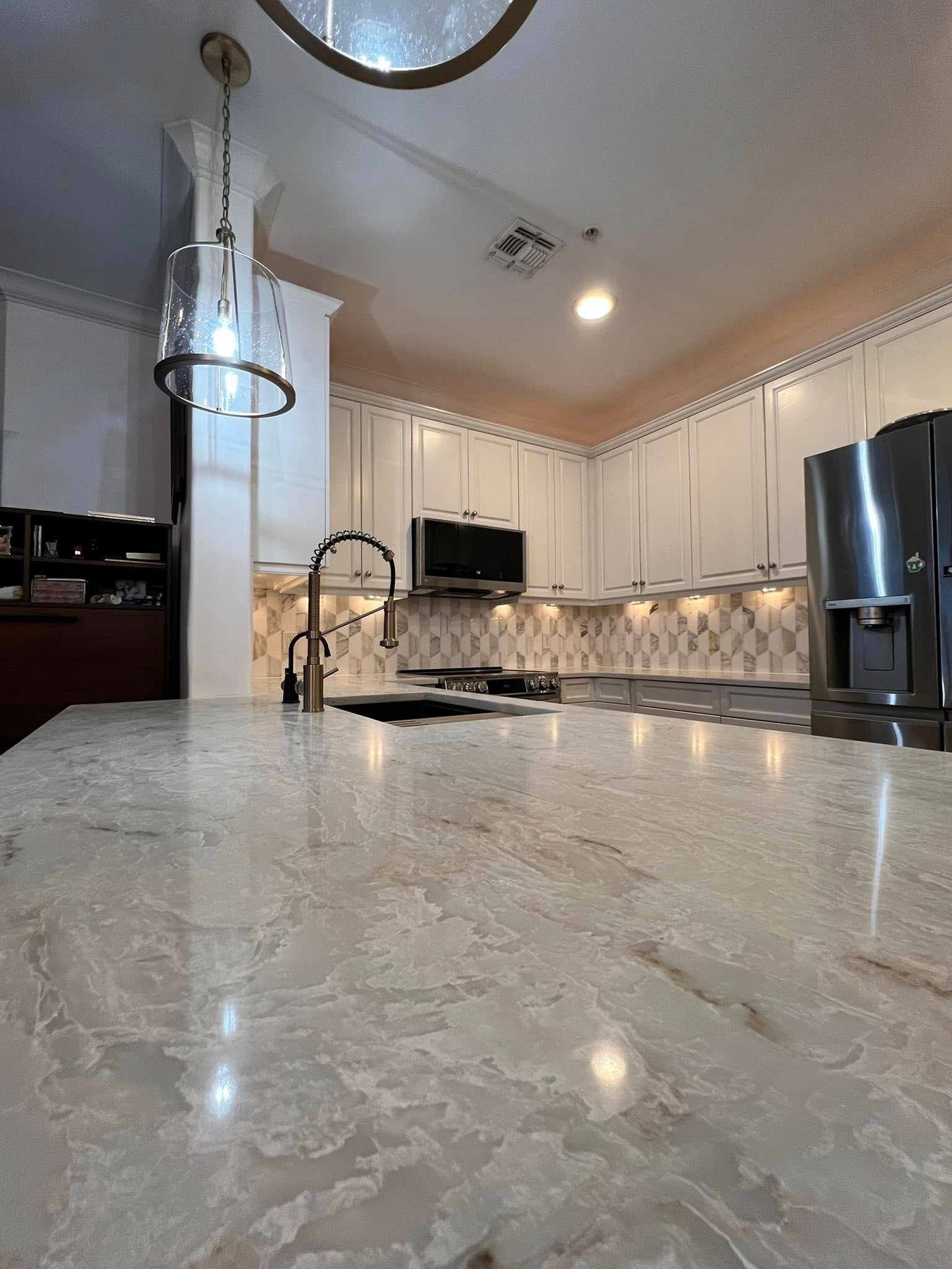 A kitchen with white cabinets, granite counter tops, stainless steel appliances and a sink