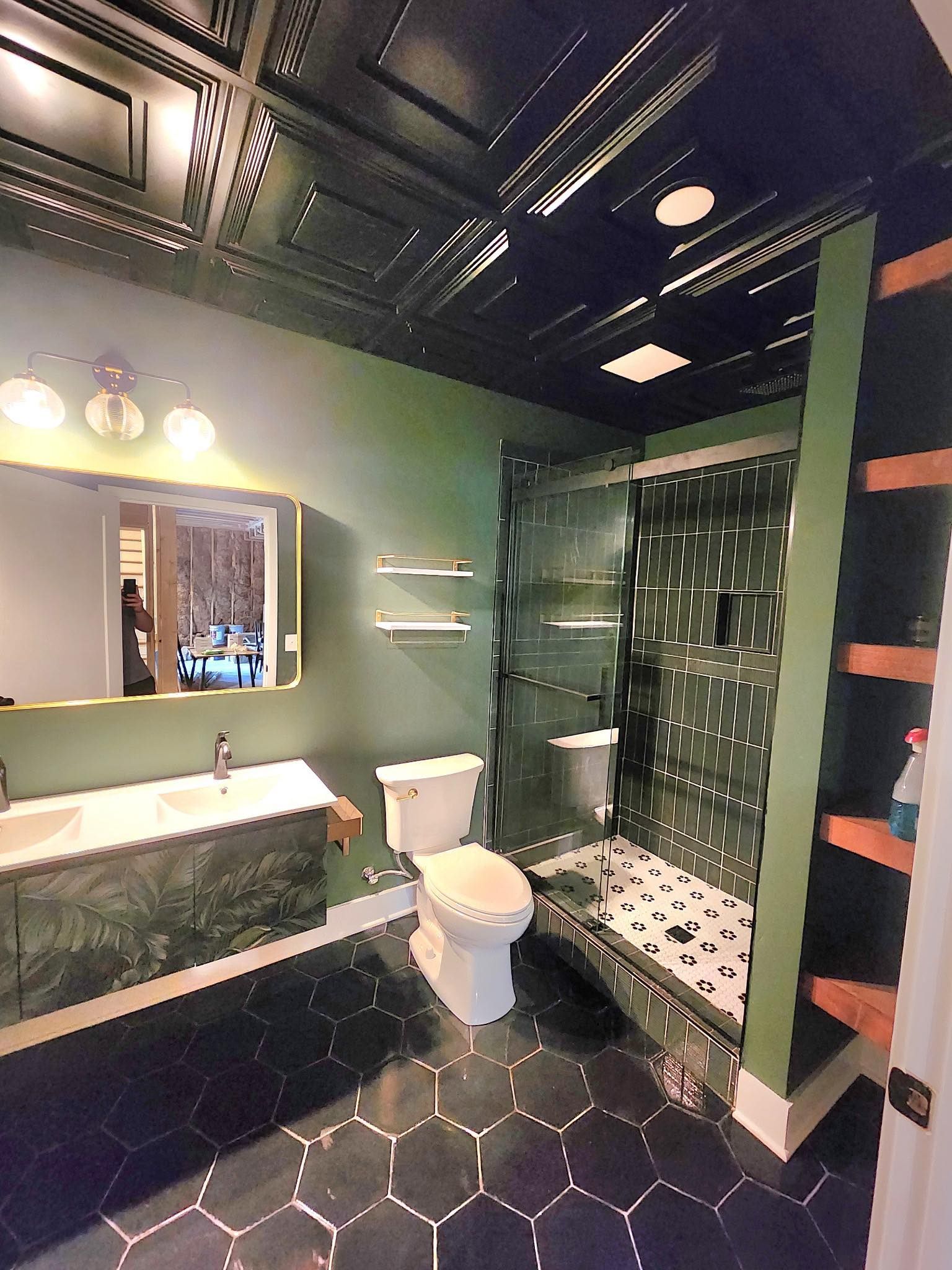 A bathroom with a toilet, sink, shower and mirror