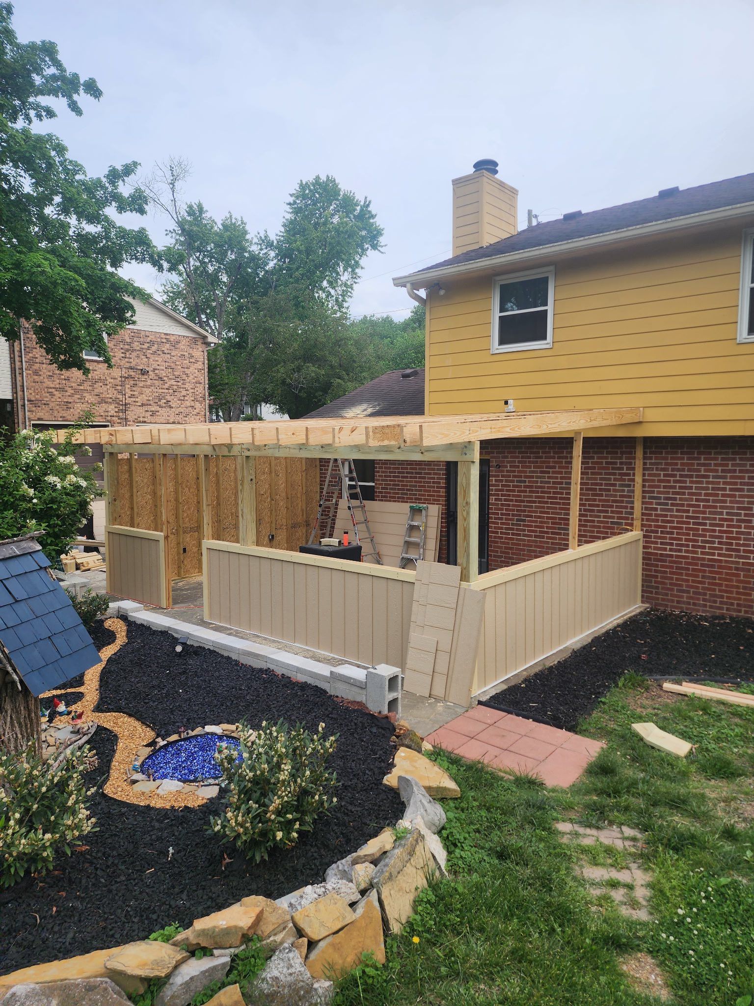 A yellow house with a wooden pergola in the backyard