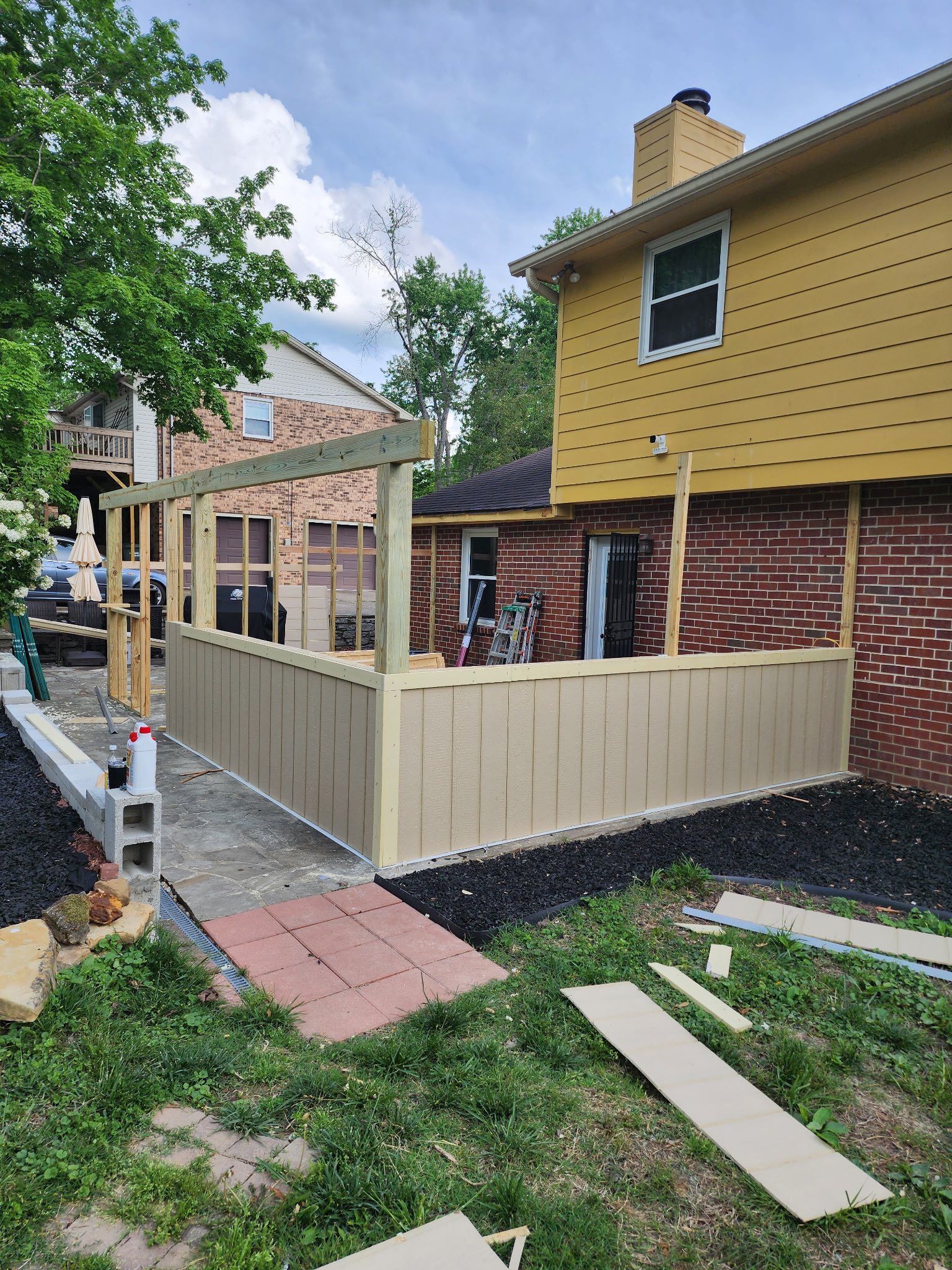A wooden fence is being built in the backyard of a house