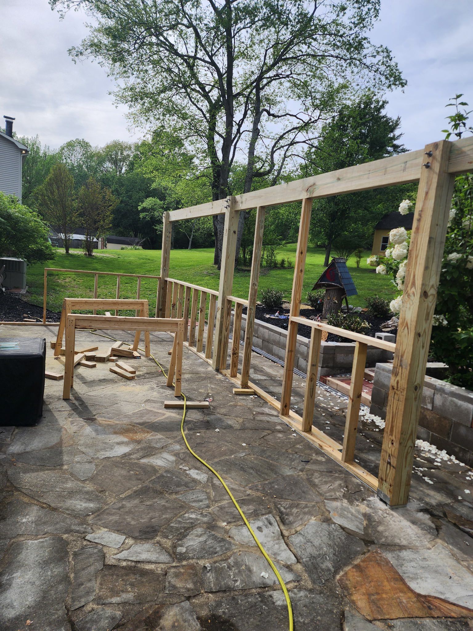 A wooden fence is being built in the backyard of a house