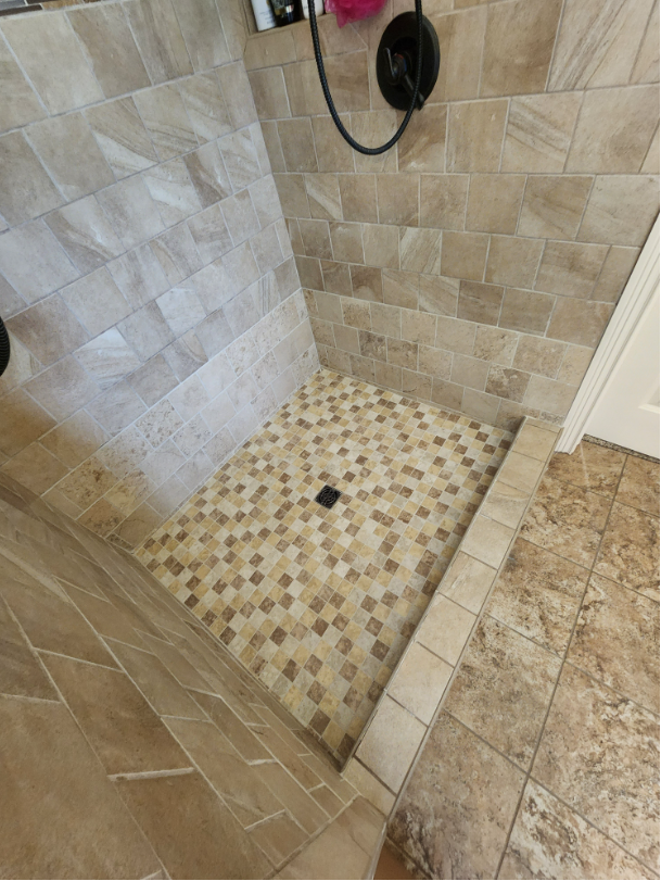 A walk in shower with a tiled floor and a shower head