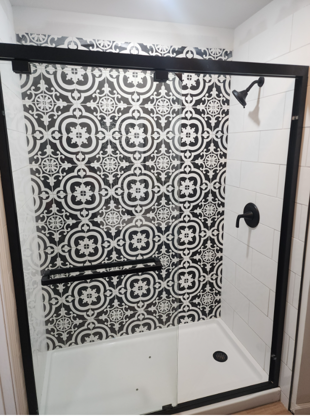A black and white shower with a sliding glass door