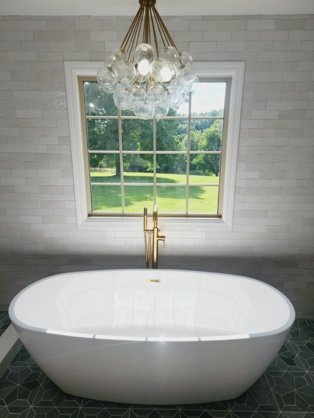 A bathtub in a bathroom with a window and a chandelier