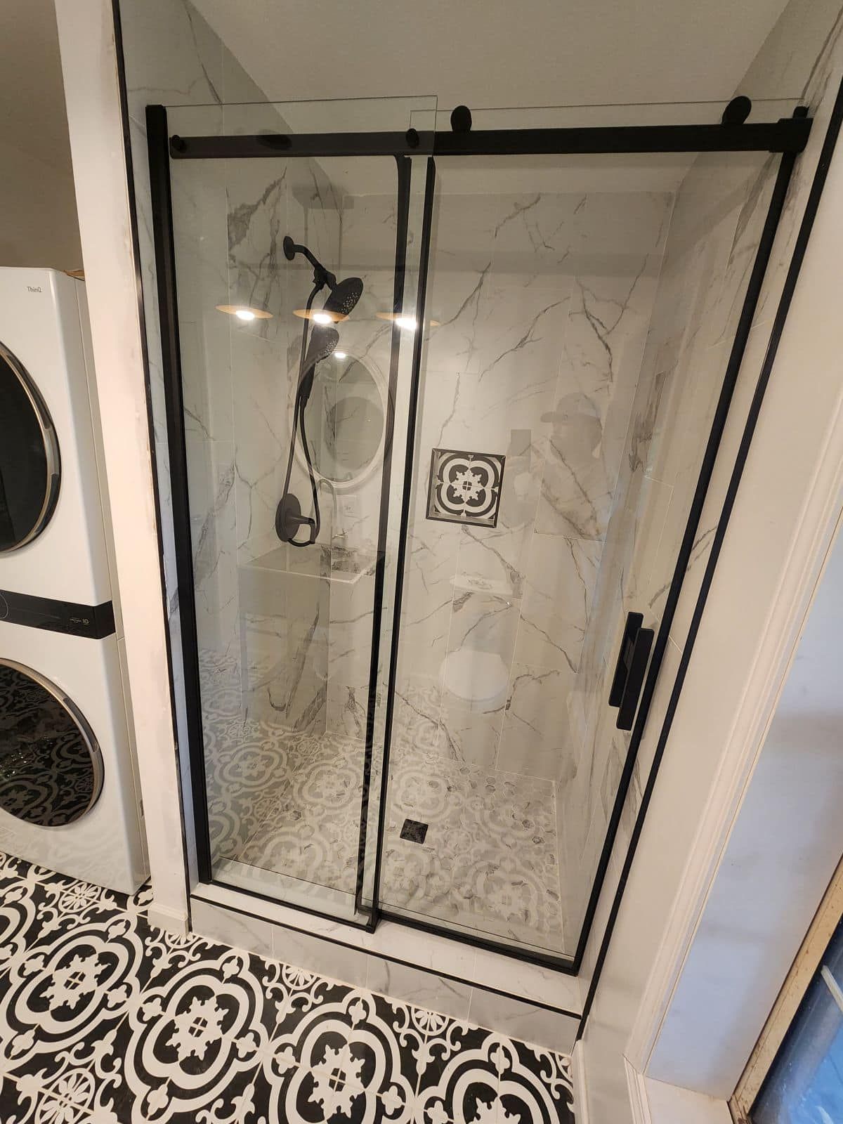 A bathroom with a sliding glass shower door and a washer and dryer