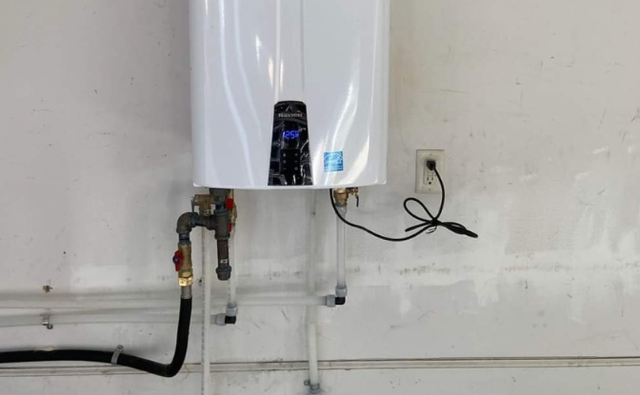 A white water heater is hanging on a white wall.