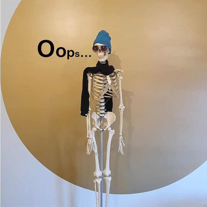 Skeleton wearing sunglasses, a blue beanie, and a black sweater, standing in front of a tan wall with a curved edge.