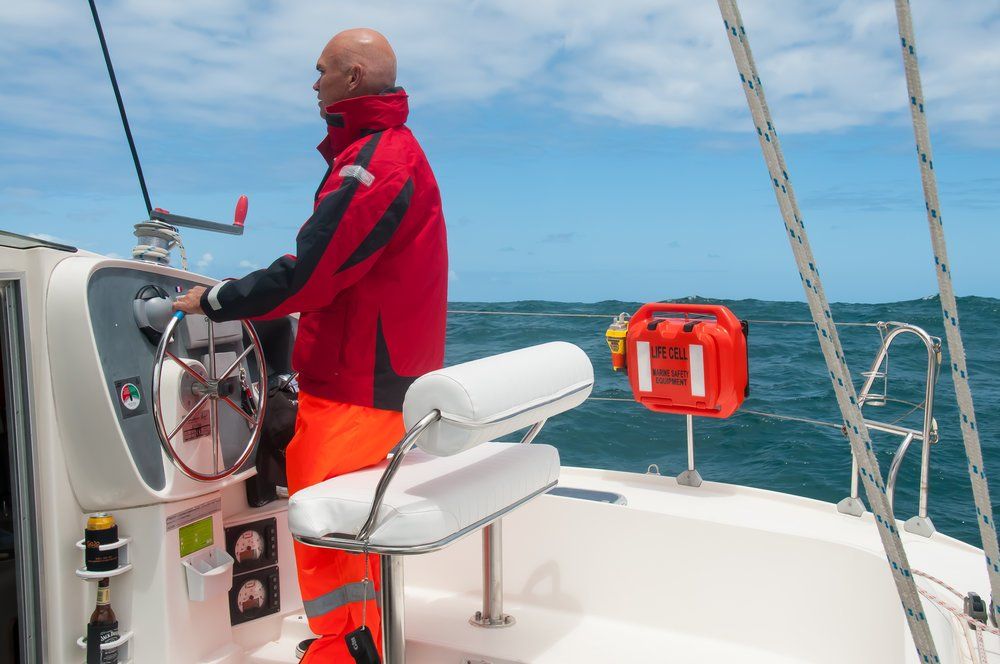 A man in a red jacket is steering a boat in the ocean. LIFECELL products