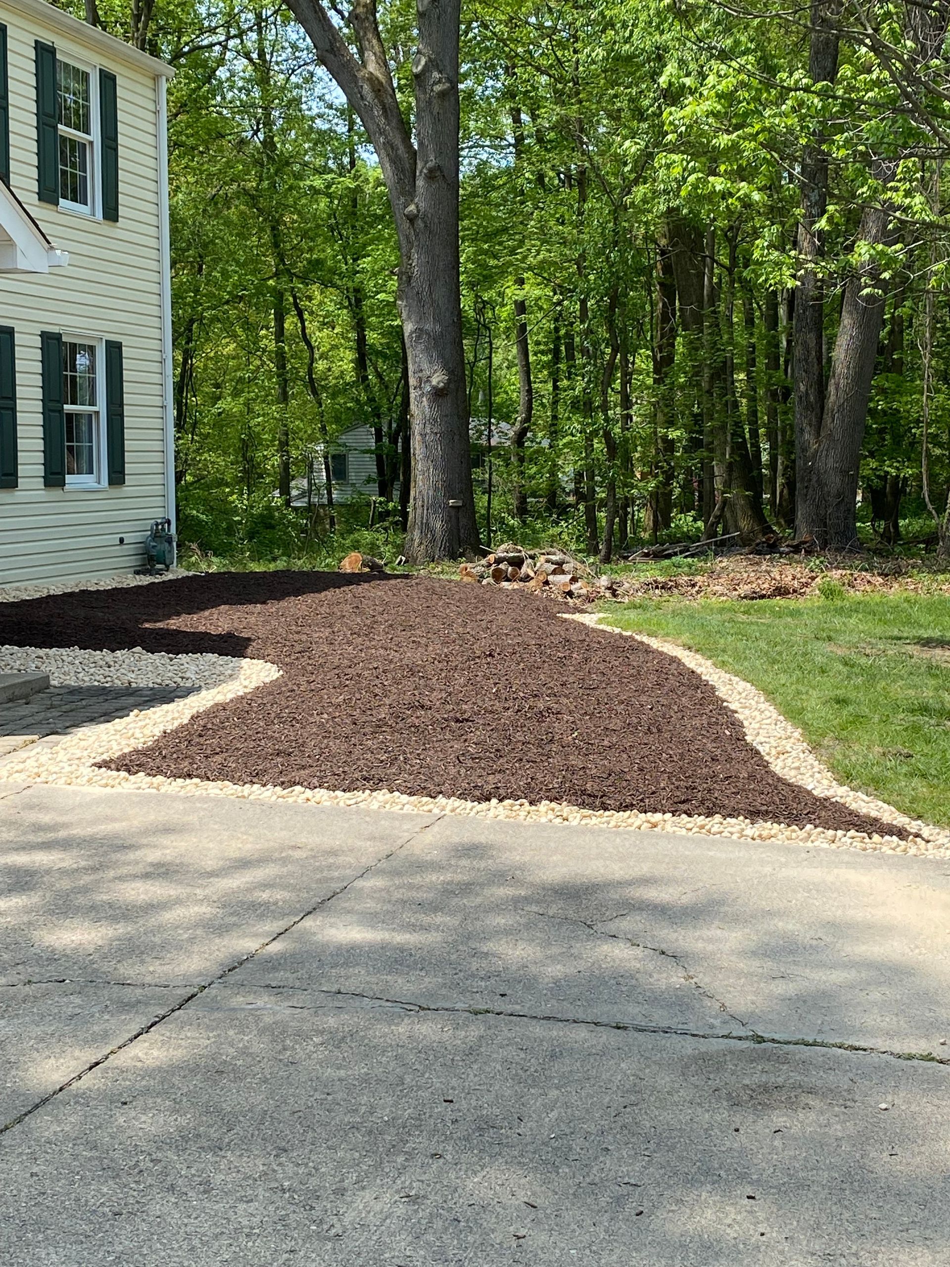 A driveway with a pile of mulch in front of a house.