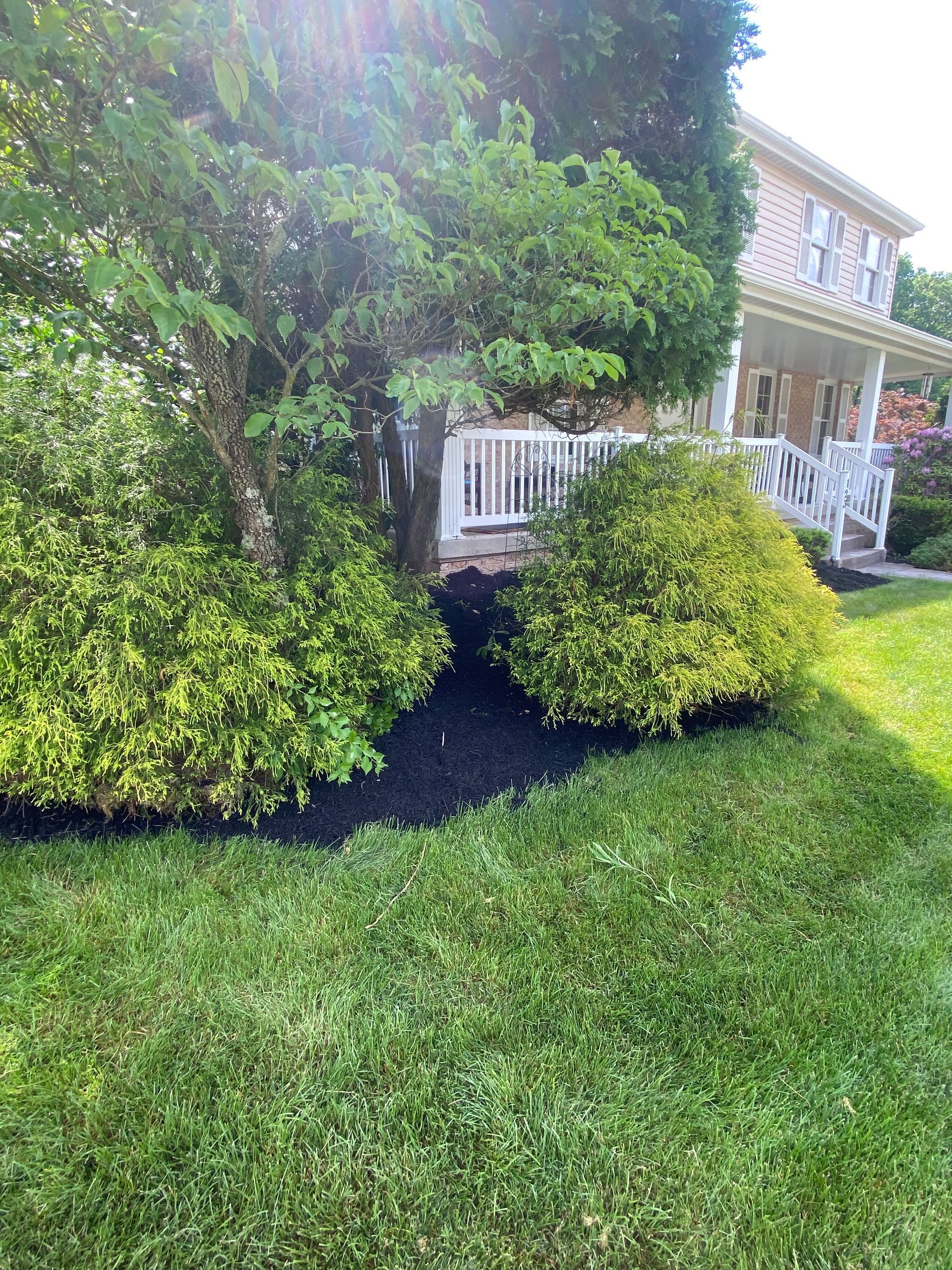 A house with a porch and a lush green lawn in front of it.