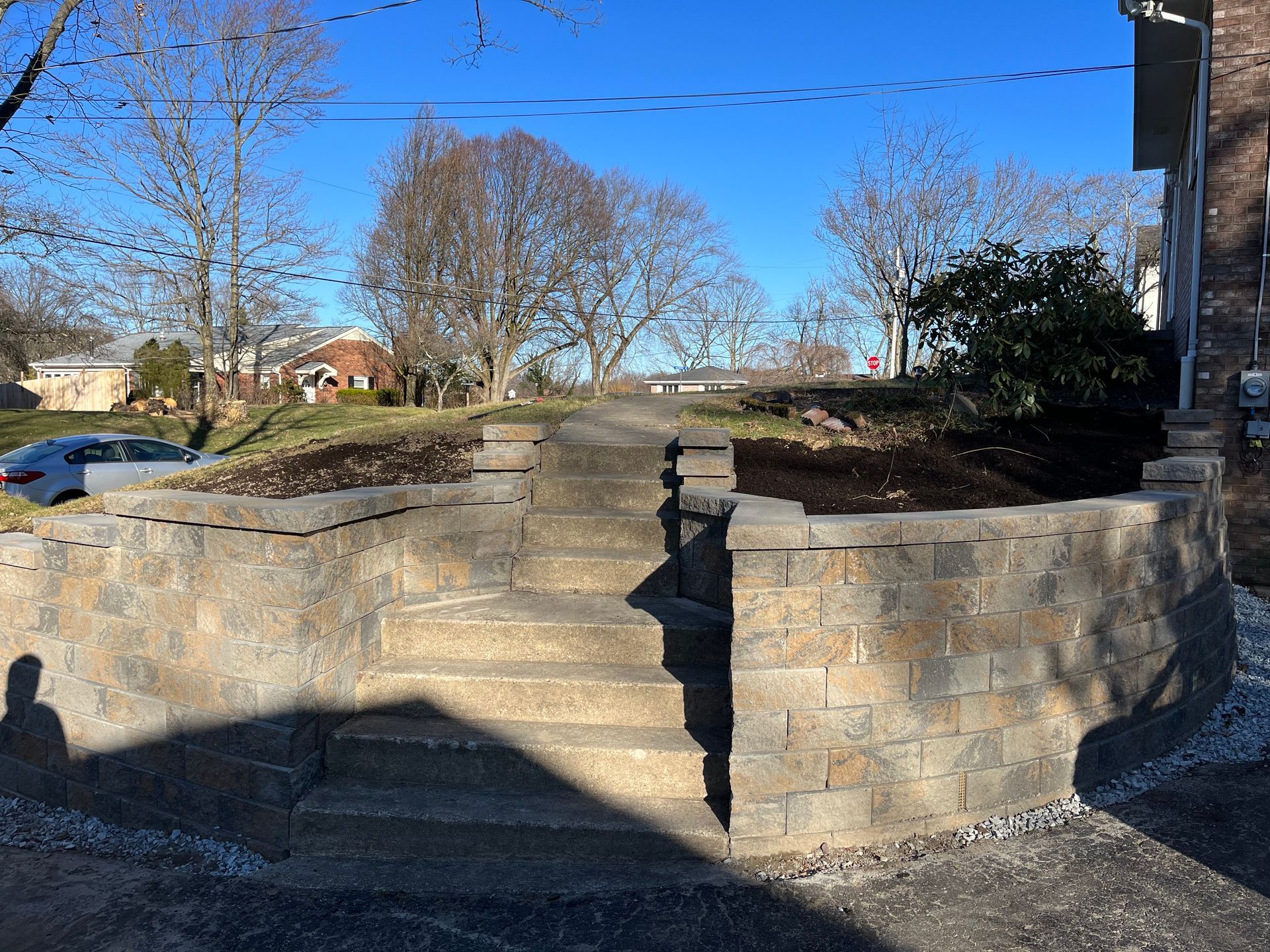 A stone wall with stairs leading up to a house.