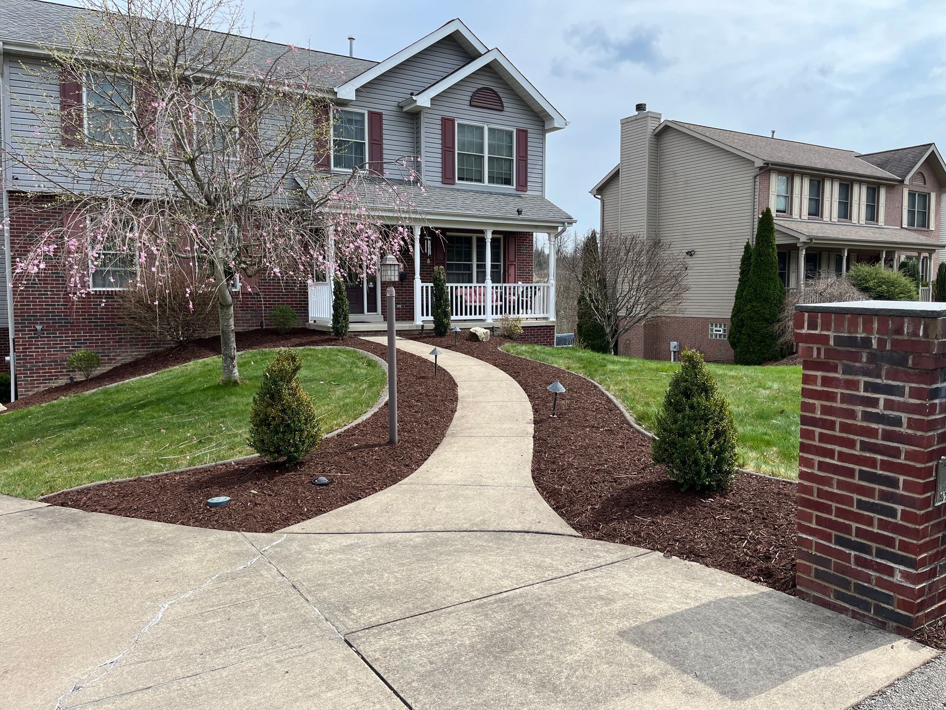 A house with a walkway leading to it and a brick wall.