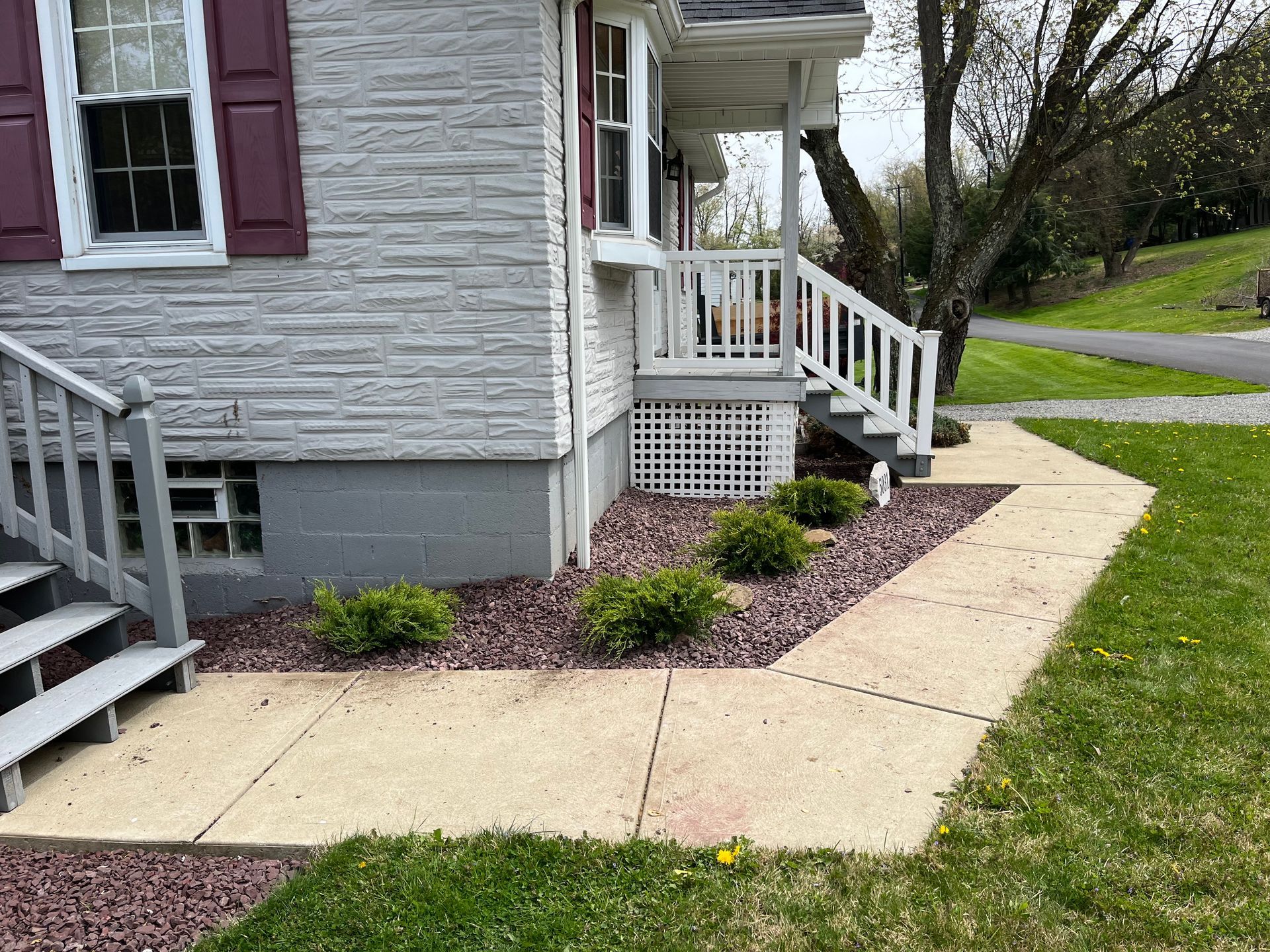 A sidewalk leading to a house with stairs and a porch.
