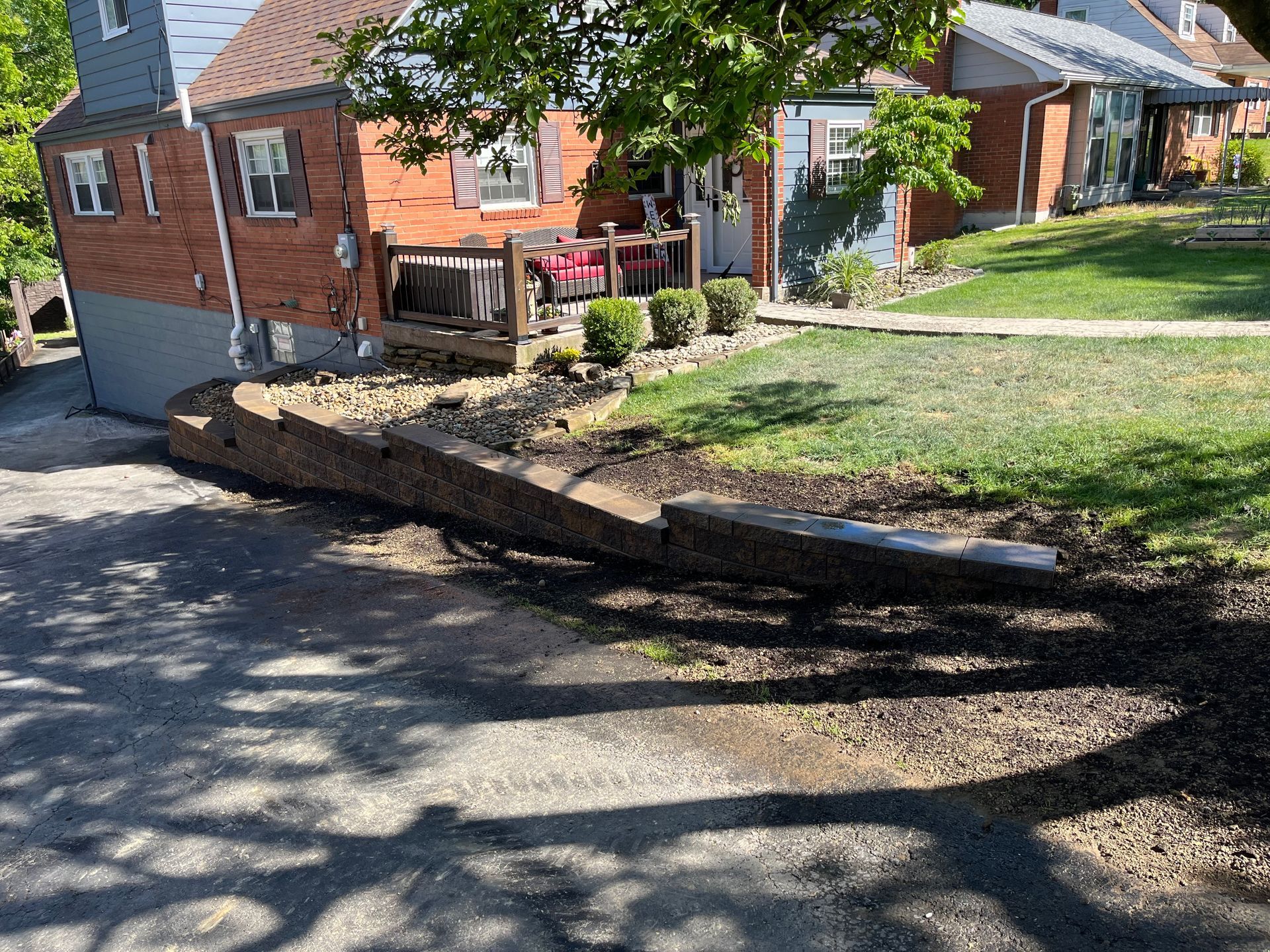 A brick house is sitting on top of a hill next to a tree.