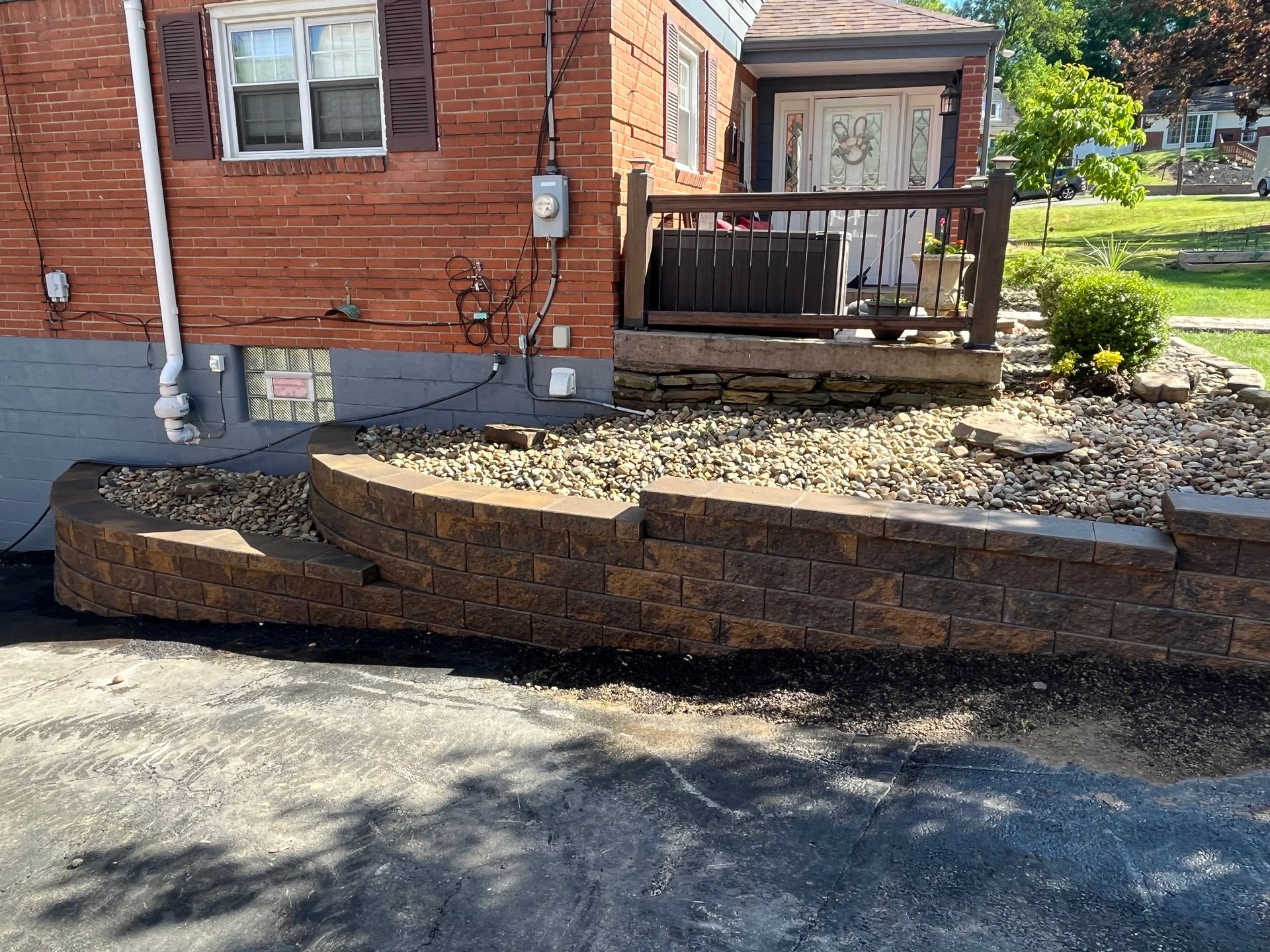 A brick house with a deck and a stone wall in front of it.
