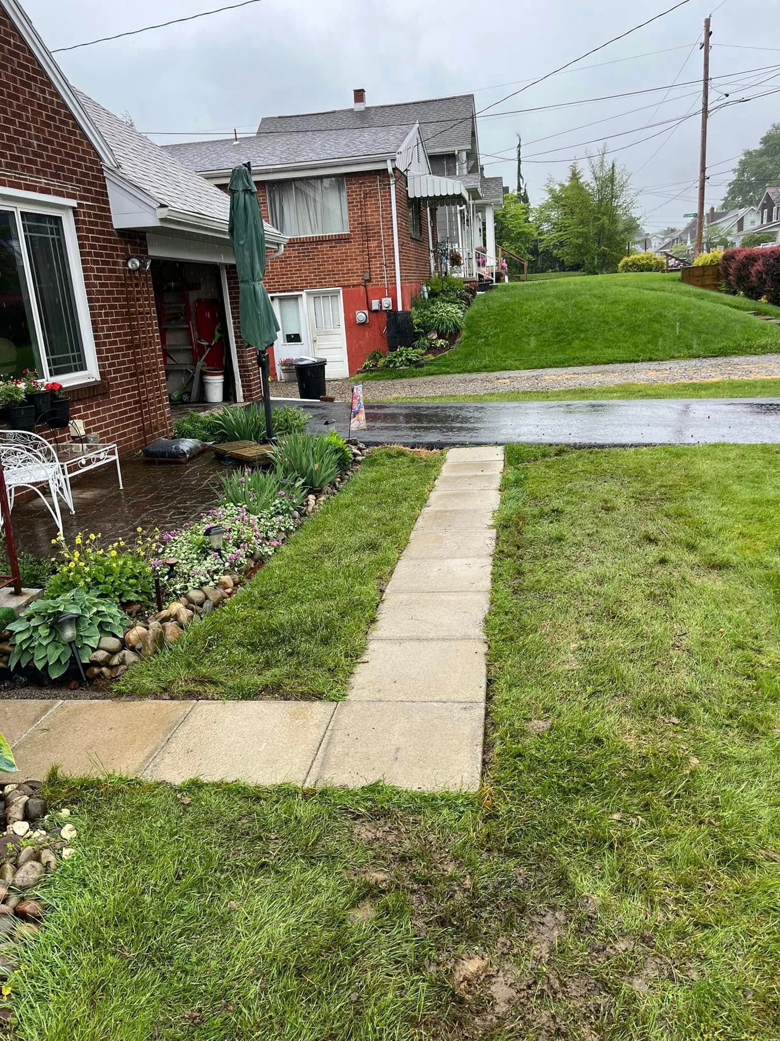 A brick house with a lush green lawn and a walkway leading to it.