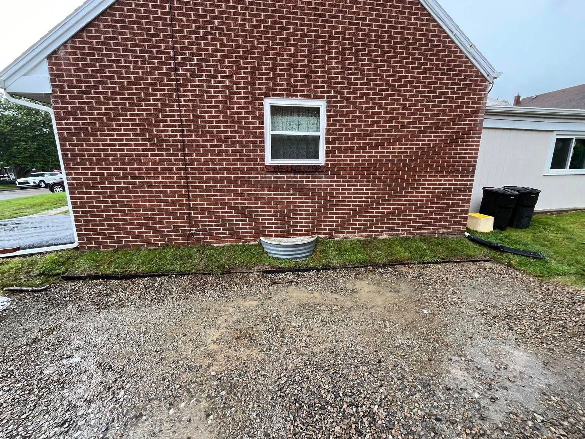 A brick house with a gravel driveway in front of it.