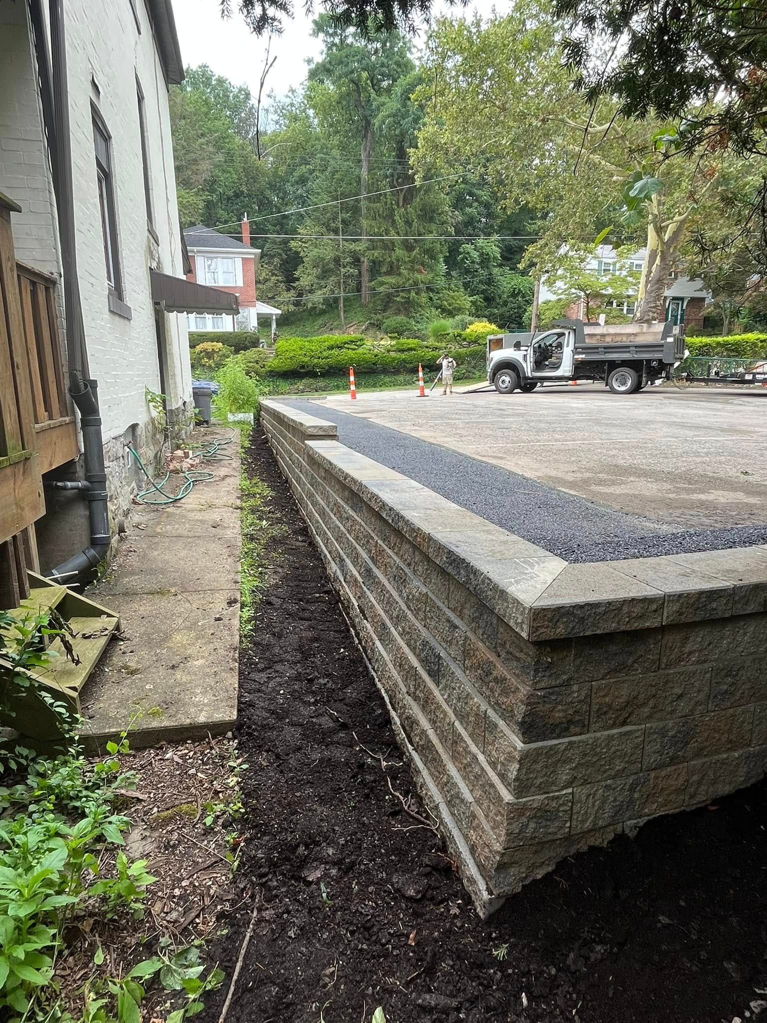 A truck is parked next to a brick wall in front of a house.