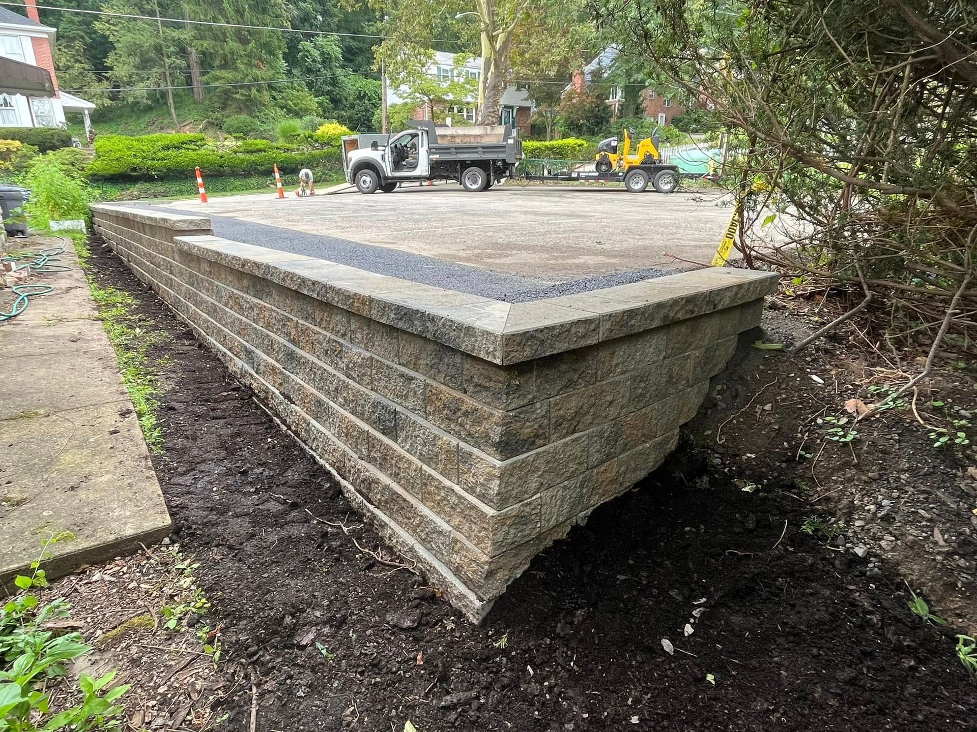 A brick wall is being built in a yard next to a dump truck.
