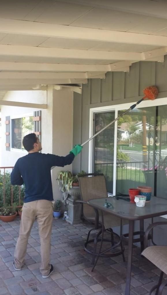 A man is standing on a porch holding a long pole.