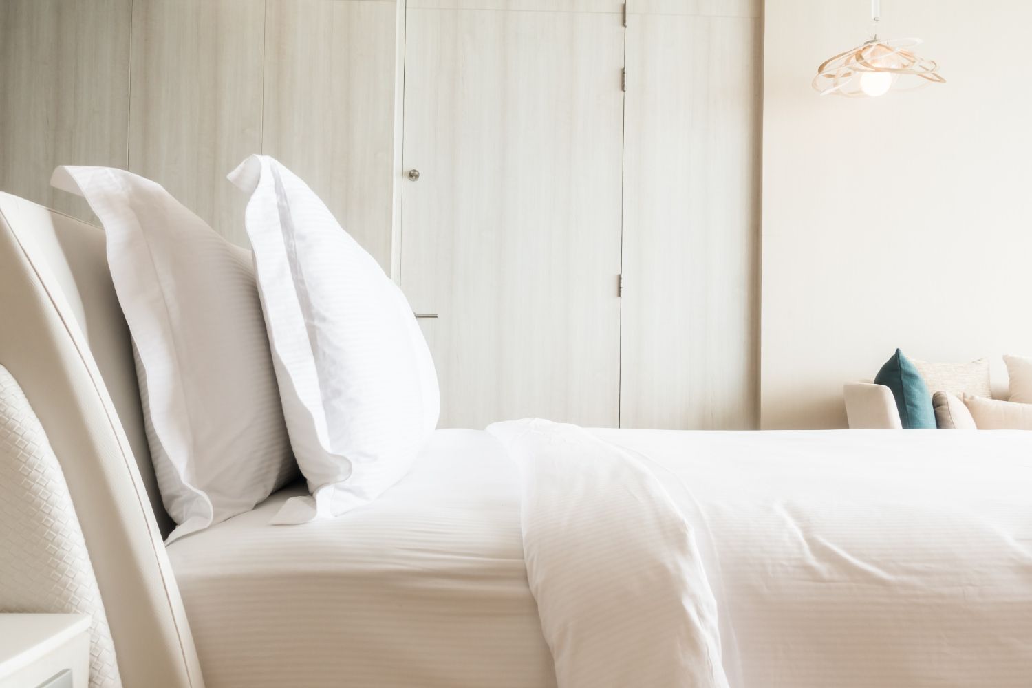 A bed with white sheets and pillows in a hotel room.