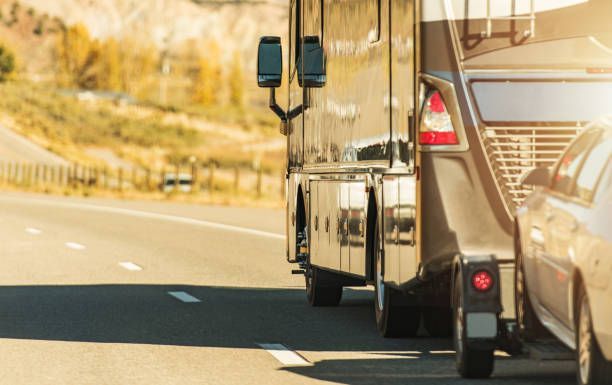 RV towing a car on a highway in sunny landscape.