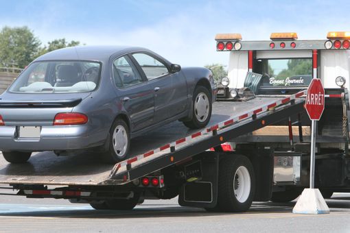 Tow truck loading a blue sedan, with an 