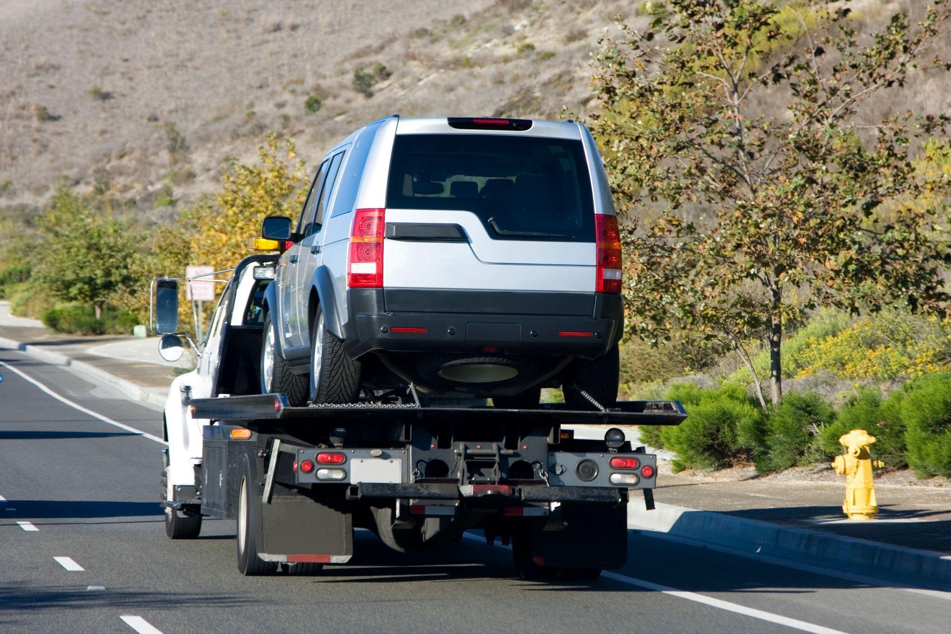 SUV being towed on a flatbed tow truck on a highway.