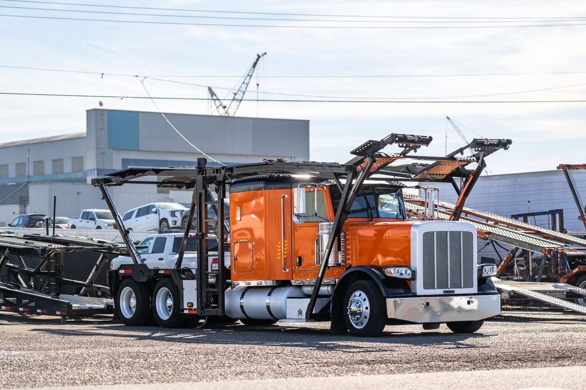 Orange car carrier truck loaded with vehicles on a sunny day.